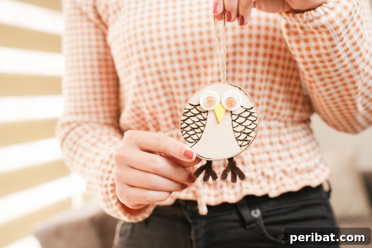 A proud woman holds up her beautifully finished wood slice owl ornament, showcasing the detailed craftsmanship and rustic appeal.