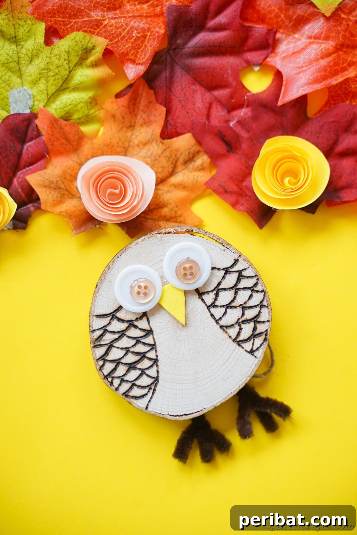 A rustic wood slice owl, adorned with button eyes and wood-burned feathers, rests on a vibrant yellow paper mat, ready to find its perfect spot in your home.