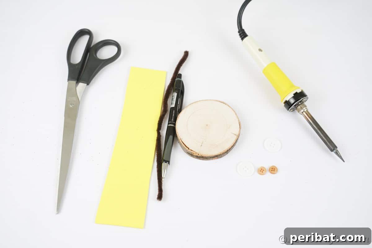 A neatly organized collection of craft supplies, including scissors, vibrant yellow foam paper, brown pipe cleaners, a rustic wood slice, and a wood burning tool, all laid out on a clean white table, ready for crafting.