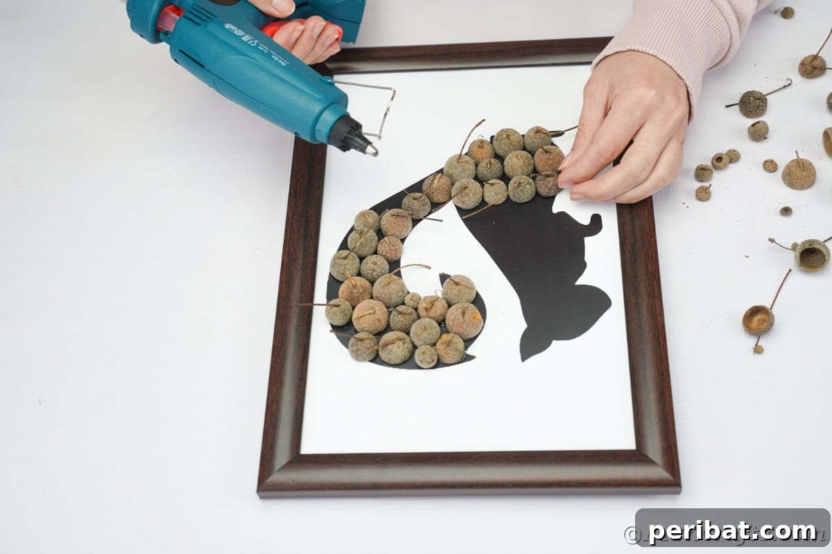 Charming Framed Squirrel with Acorn Cap Wall Decor 12 Hands adding acorn caps to printed template in frame