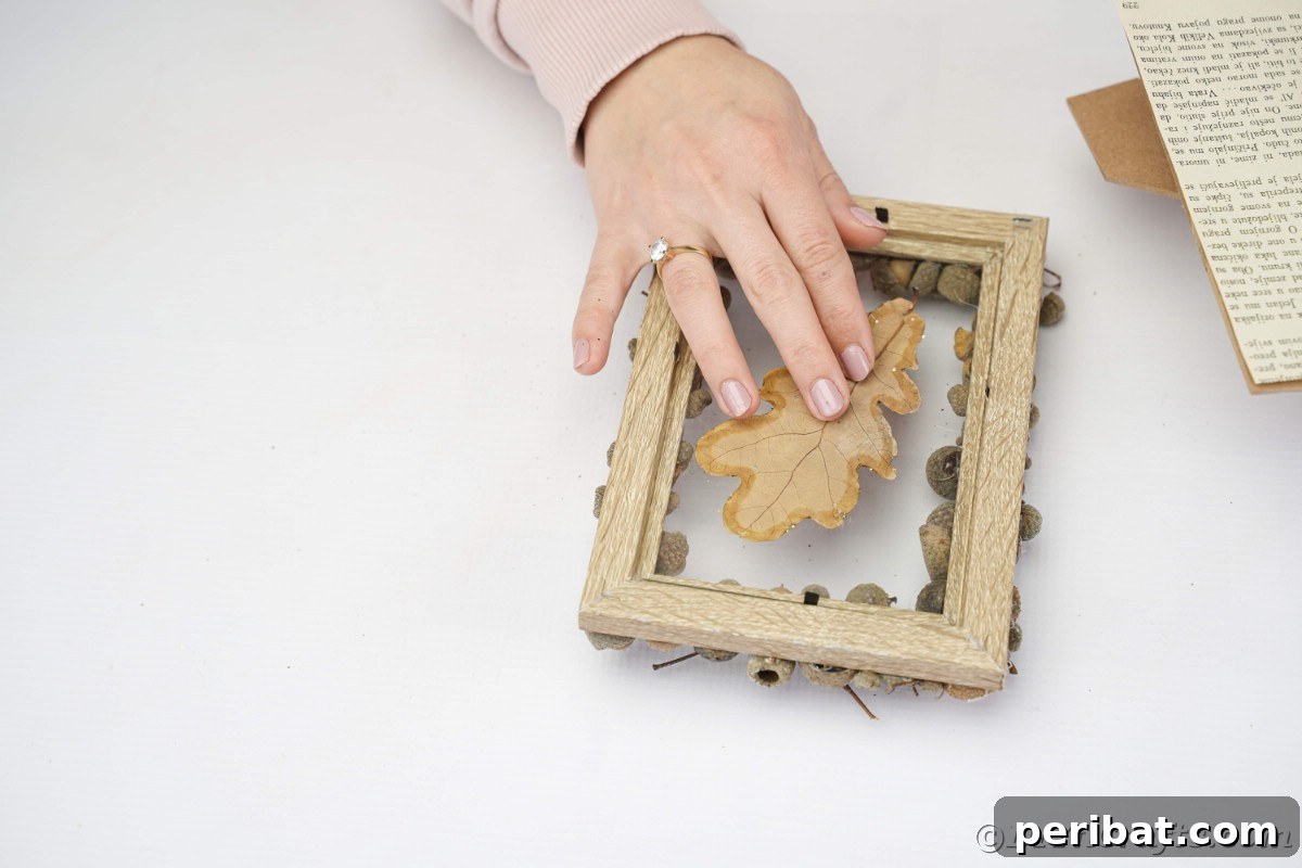 Hand holding a leaf on top of the picture frame glass, preparing for the final assembly of the artwork.
