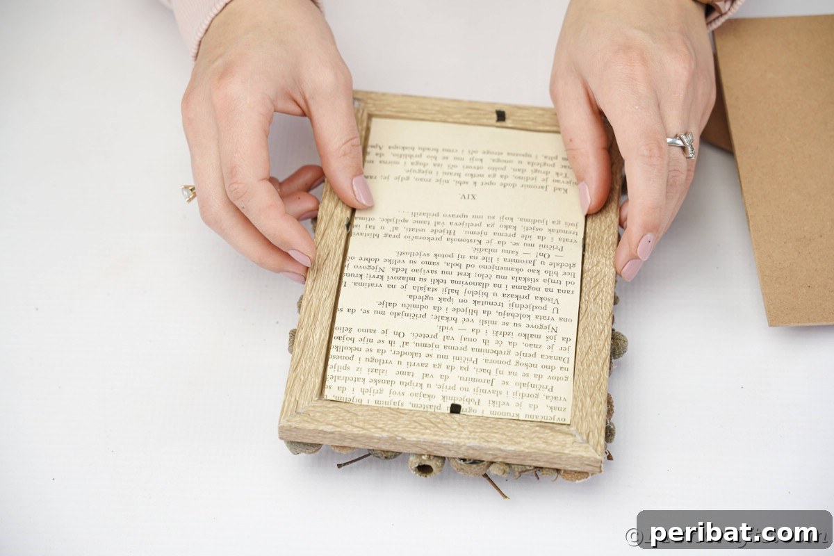 Hand carefully placing the book page over the back of the frame, ready to secure the backing.