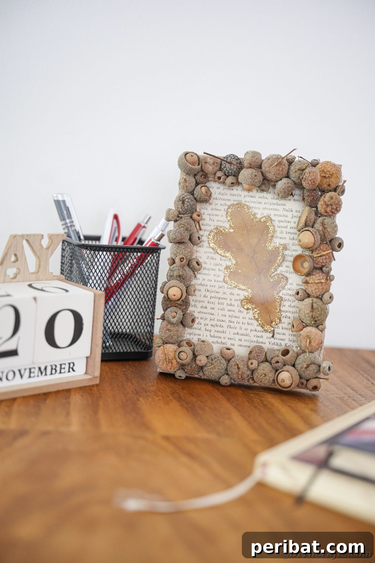 Desk with calendar blocks next to a rustic picture frame featuring a book page and leaf design, perfect for fall office decor.