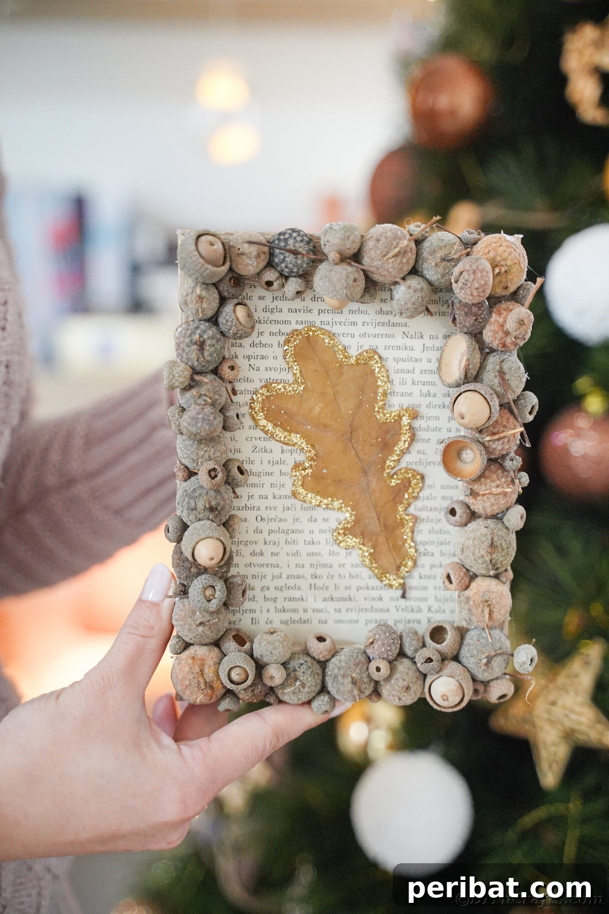 Woman in a pink sweater holding an acorn cap frame, presenting a handmade gift idea for autumn.