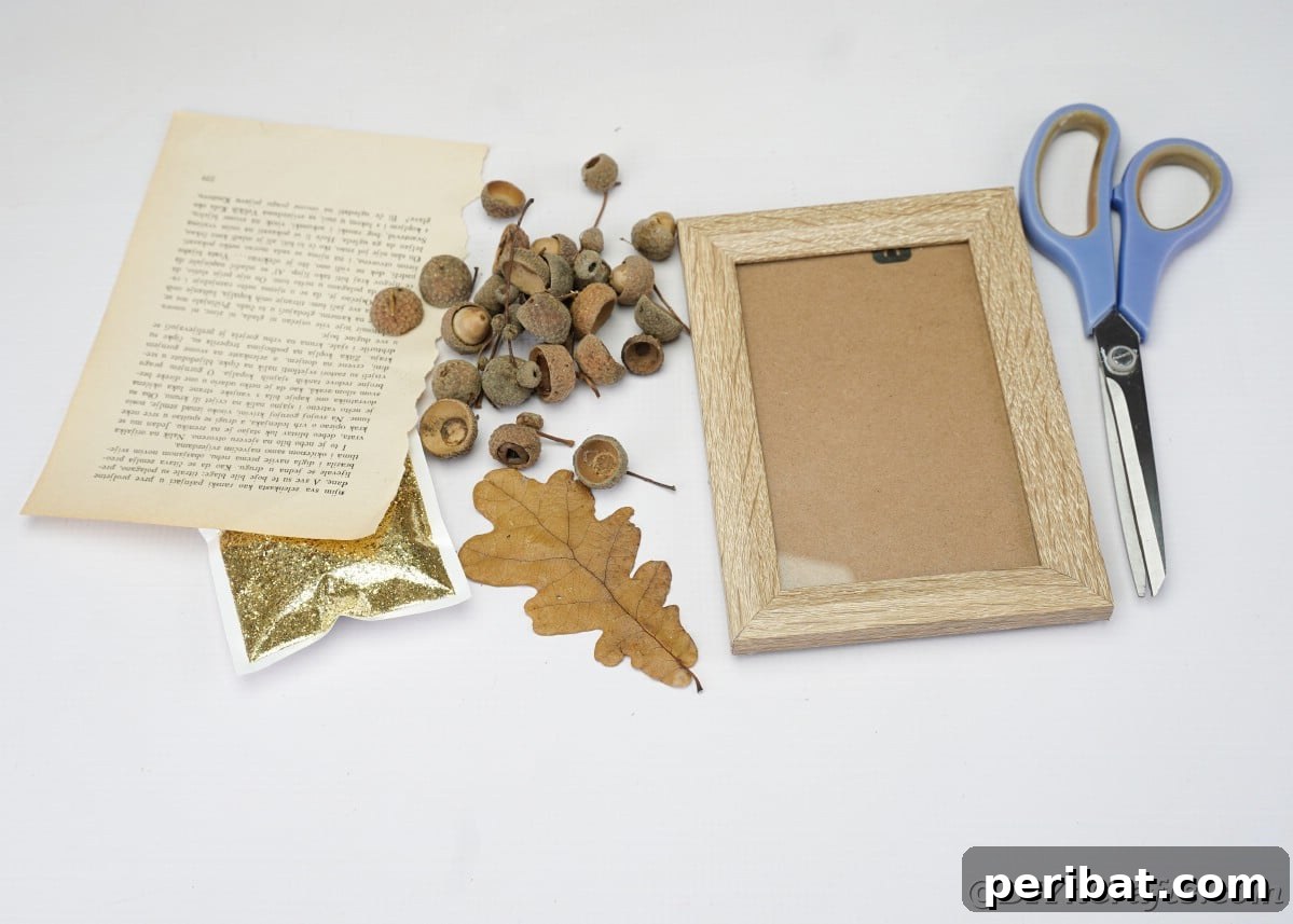 Arrangement of craft supplies: picture frame, acorn caps, old book pages, leaf, glitter, and scissors on a white table, ready for a DIY project.