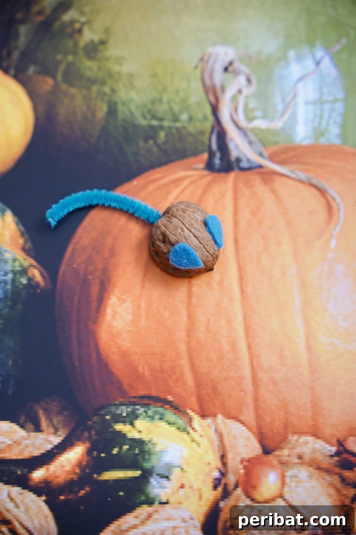 Walnut Wonders: Upcycled Shell Mouse Art 18 A walnut shell mouse displayed on a piece of fall-themed fabric, showcasing its cozy and autumnal aesthetic.