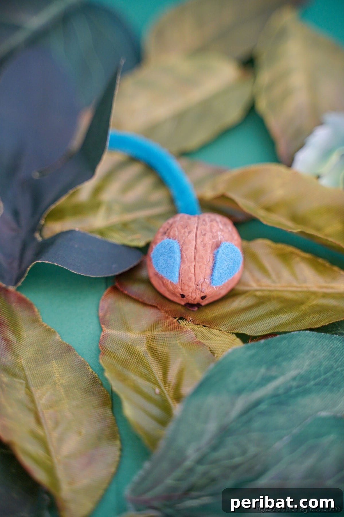 Walnut Wonders: Upcycled Shell Mouse Art 6 Walnut mouse resting on vibrant green leaves, enhancing its natural aesthetic and suggesting a connection to outdoor elements.