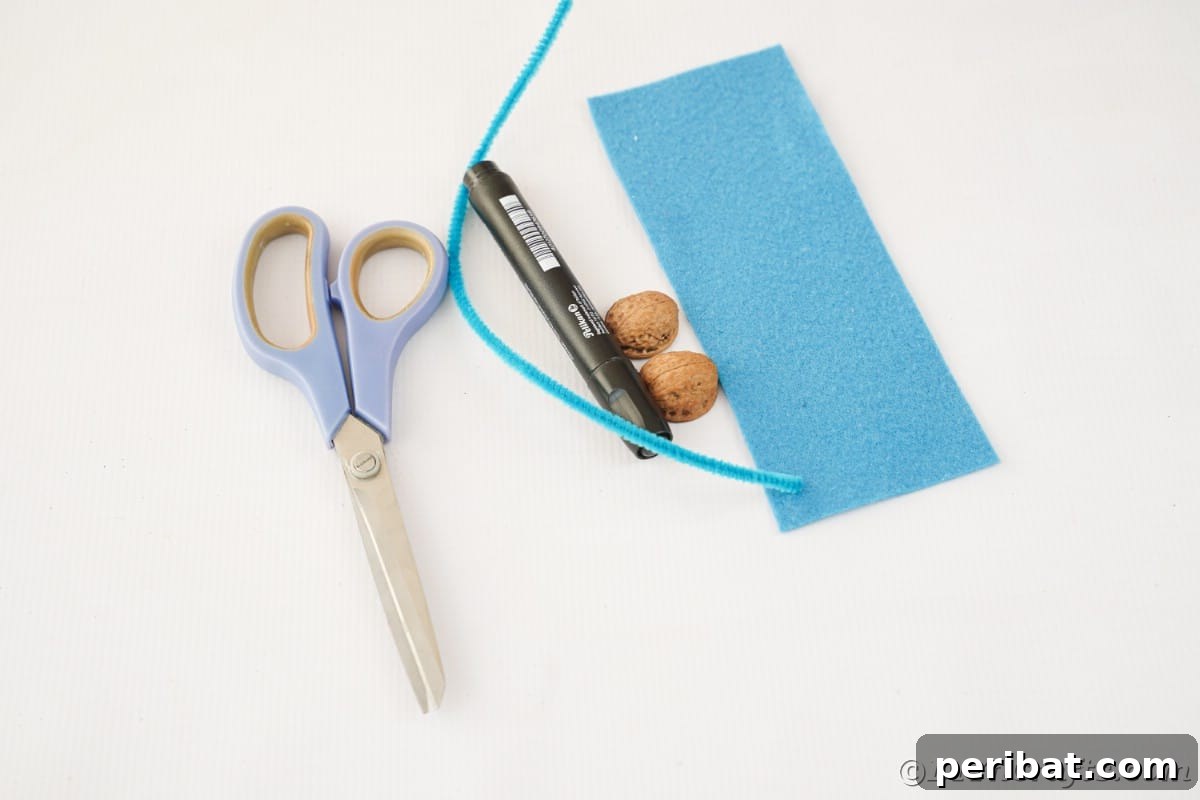 Walnut Wonders: Upcycled Shell Mouse Art 8 A crafting setup with blue felt, scissors, various walnut shells, and a black marker arranged neatly on a white table, ready for the project.