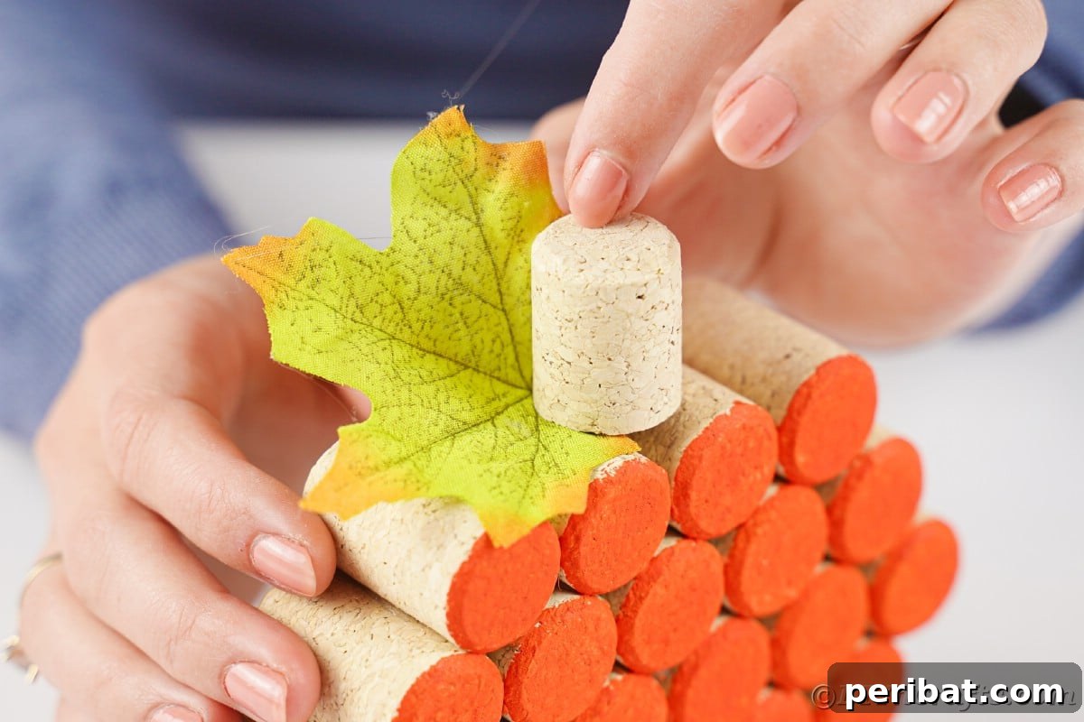 Charming Rustic Wine Cork Pumpkin Creation 14 a hand holding an additional cork on top of a larger cork pumpkin structure, adding a stem