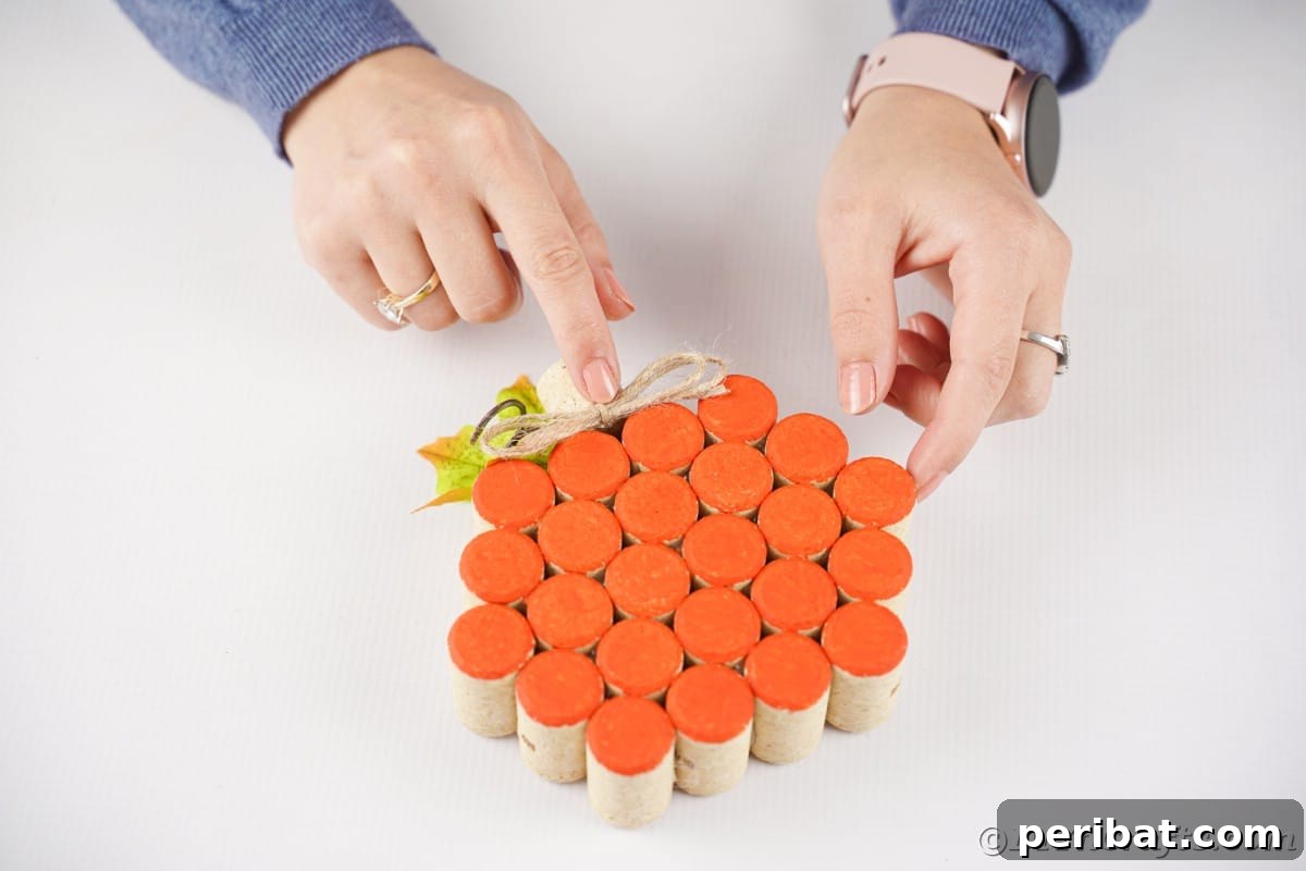 Charming Rustic Wine Cork Pumpkin Creation 15 a hand meticulously gluing a small bow onto the top of a finished cork pumpkin, adding a decorative touch