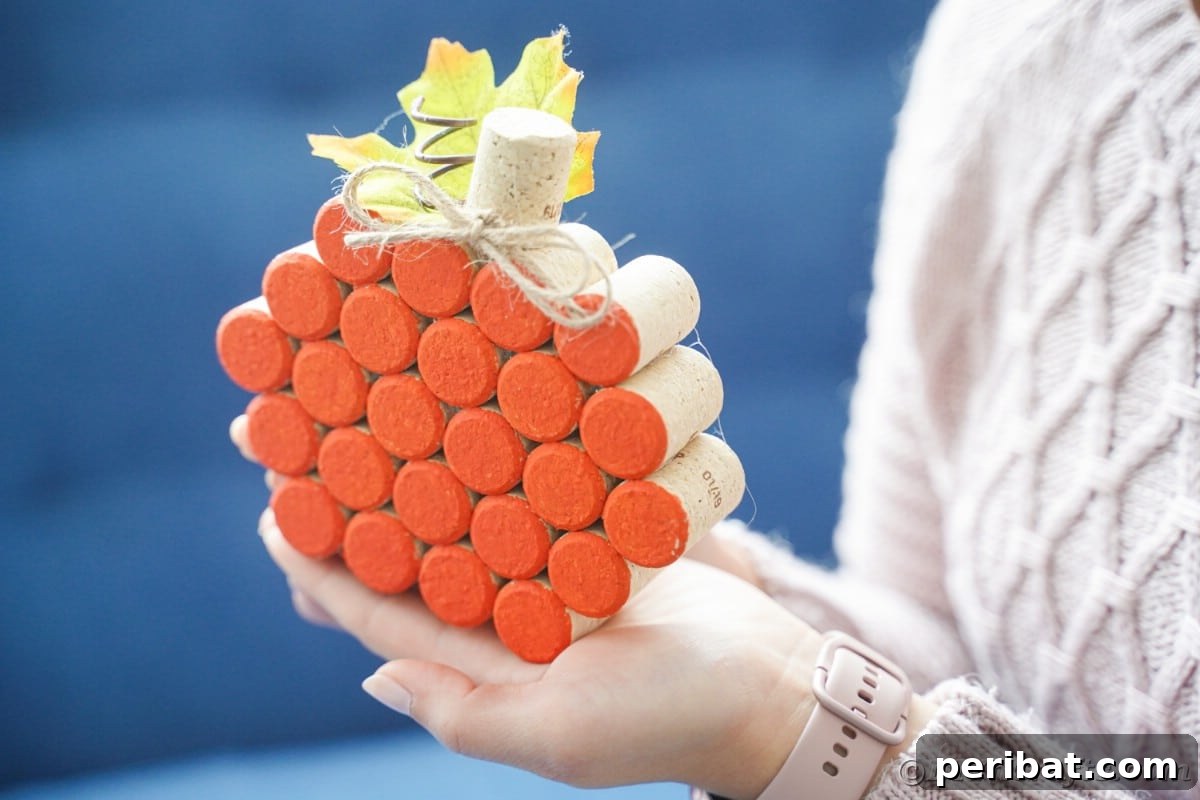 Charming Rustic Wine Cork Pumpkin Creation 16 a finished orange pumpkin crafted from wine corks held gently in hands, showcasing its handmade charm