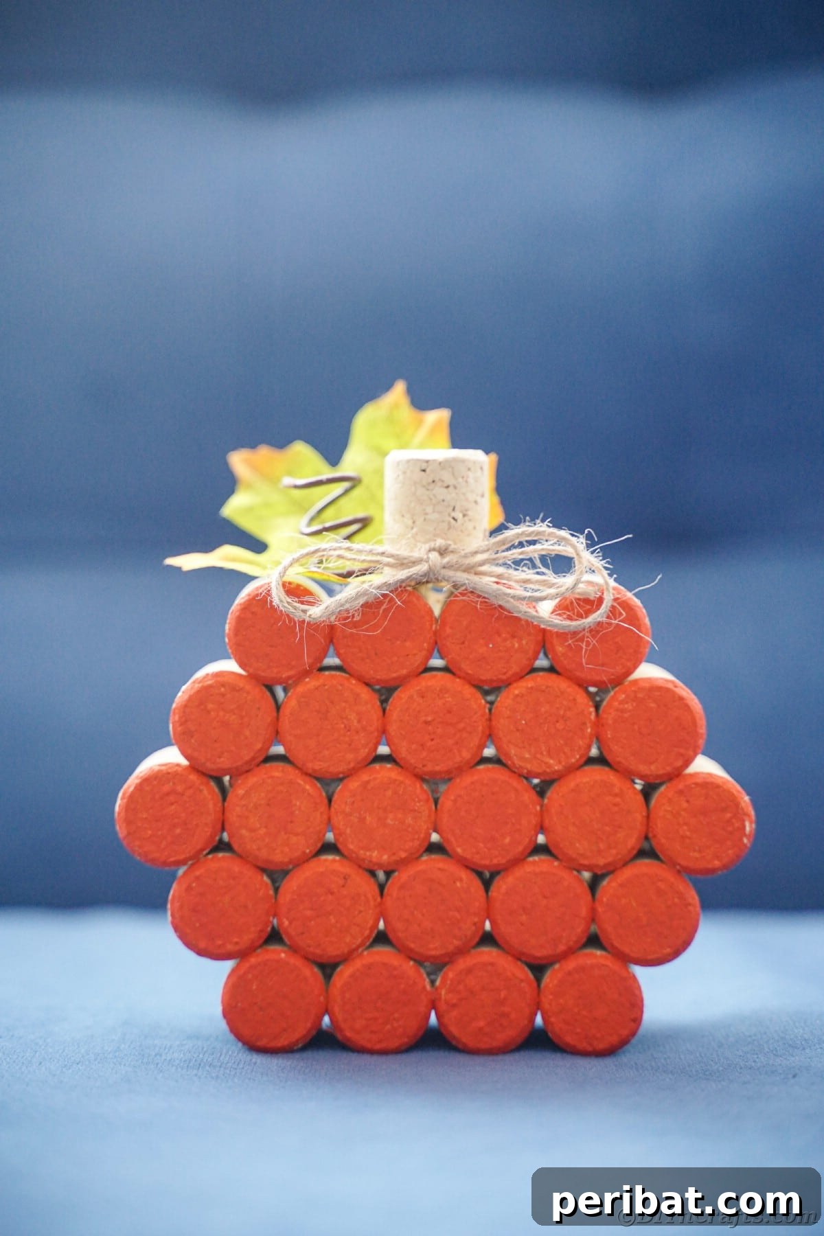Charming Rustic Wine Cork Pumpkin Creation 6 a vibrant orange wine cork pumpkin rests gracefully on a blue table, contrasting beautifully with its surroundings