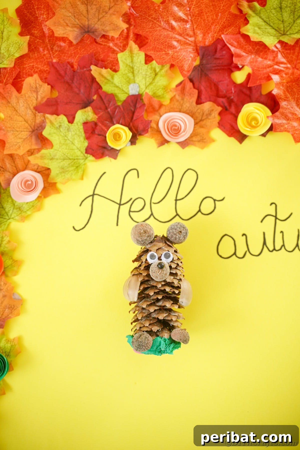 Pinecone bear on a yellow table with fake autumn leaves, indicating seasonal decor