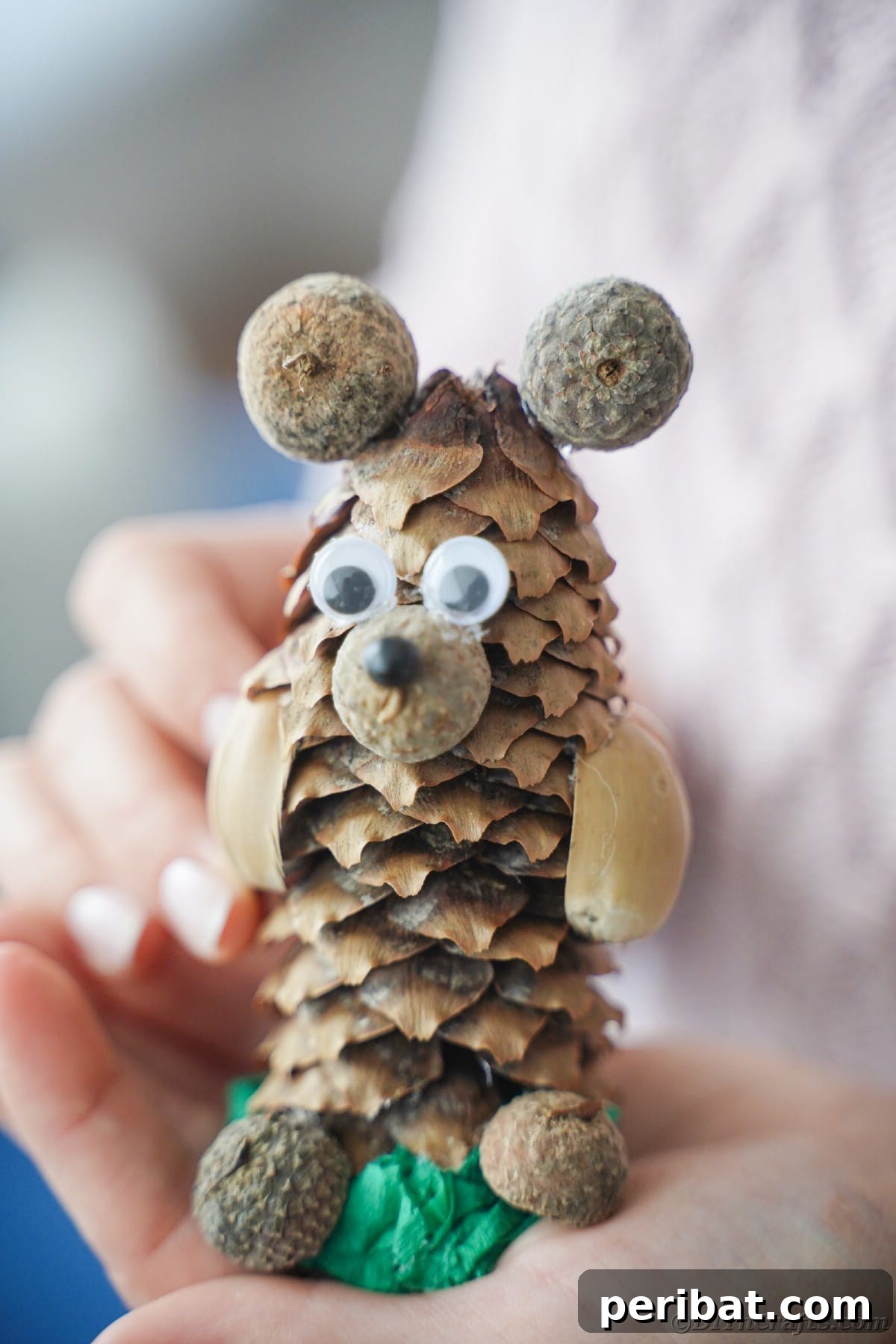 A hand gently holding a finished pinecone bear craft, showcasing its size and detail