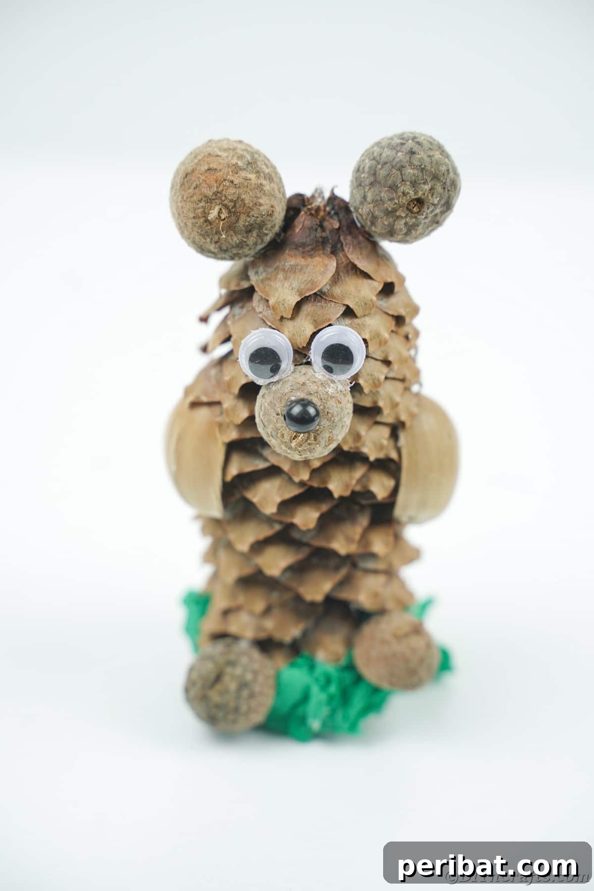 Pinecone bear on a simple green base sitting on a white table