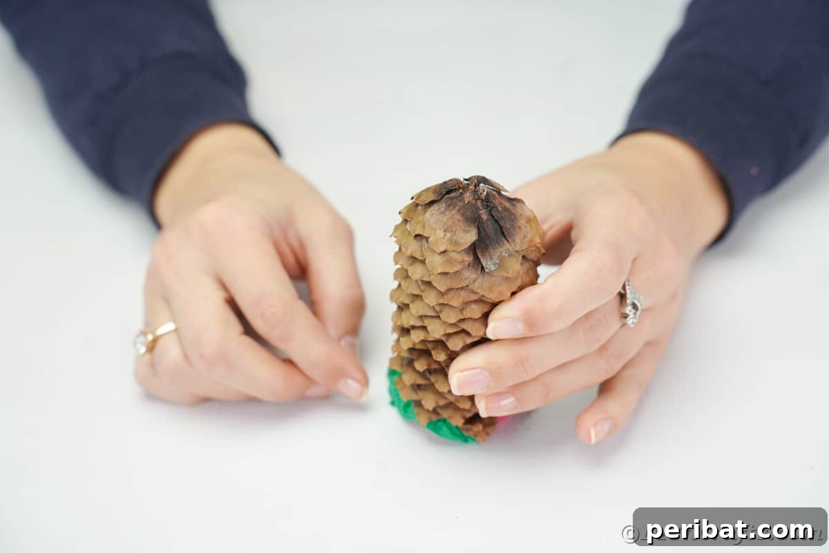 A pinecone standing upright on a green tissue paper base inside a bottle cap