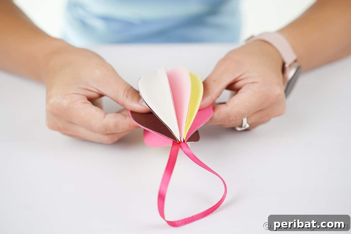 Whimsical Paper Evergreen Decor 14 Hands gently fluffing out the individual paper sections of a completed ornament, giving it a full, three-dimensional look