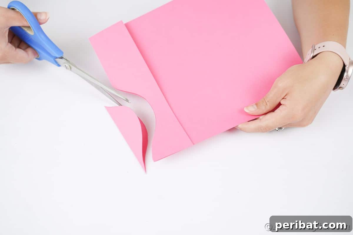 Pink craft paper being precisely cut with scissors along a drawn line, demonstrating a step in ornament creation