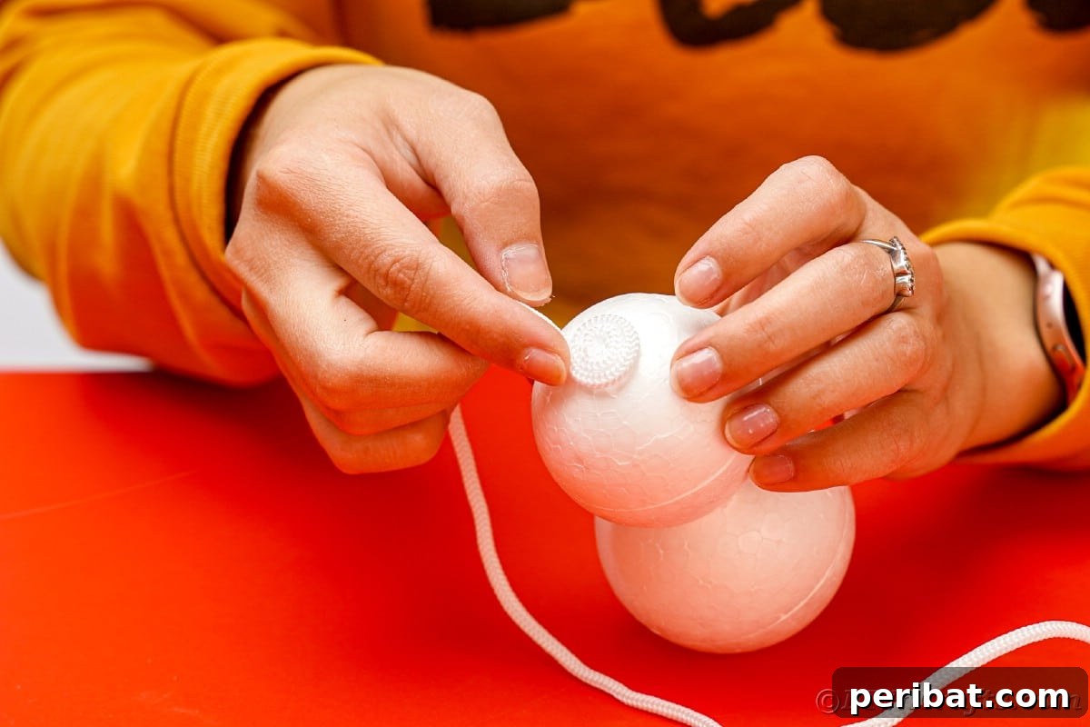 Cozy Twine Snowman Christmas Charm 11 hand holding rope on top of styrofoam ball