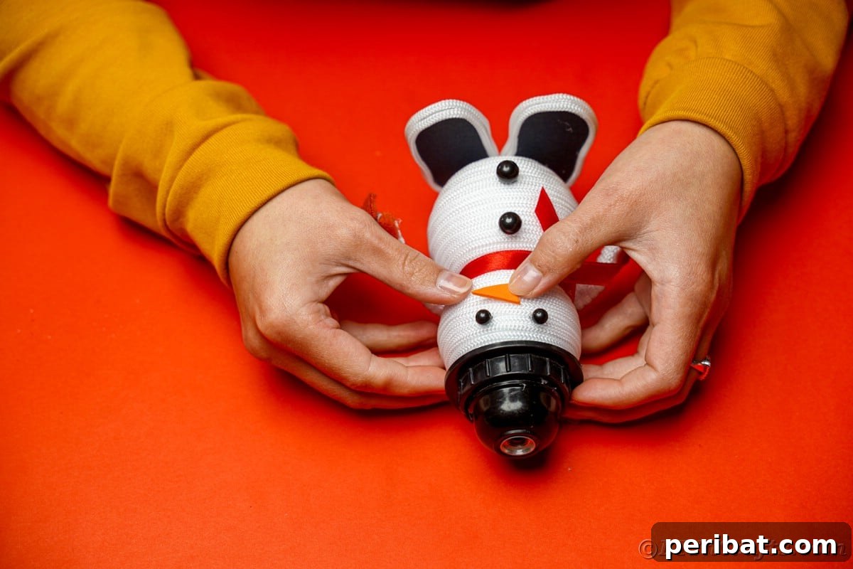 Cozy Twine Snowman Christmas Charm 23 hands adding a nose to top ball on snowman body