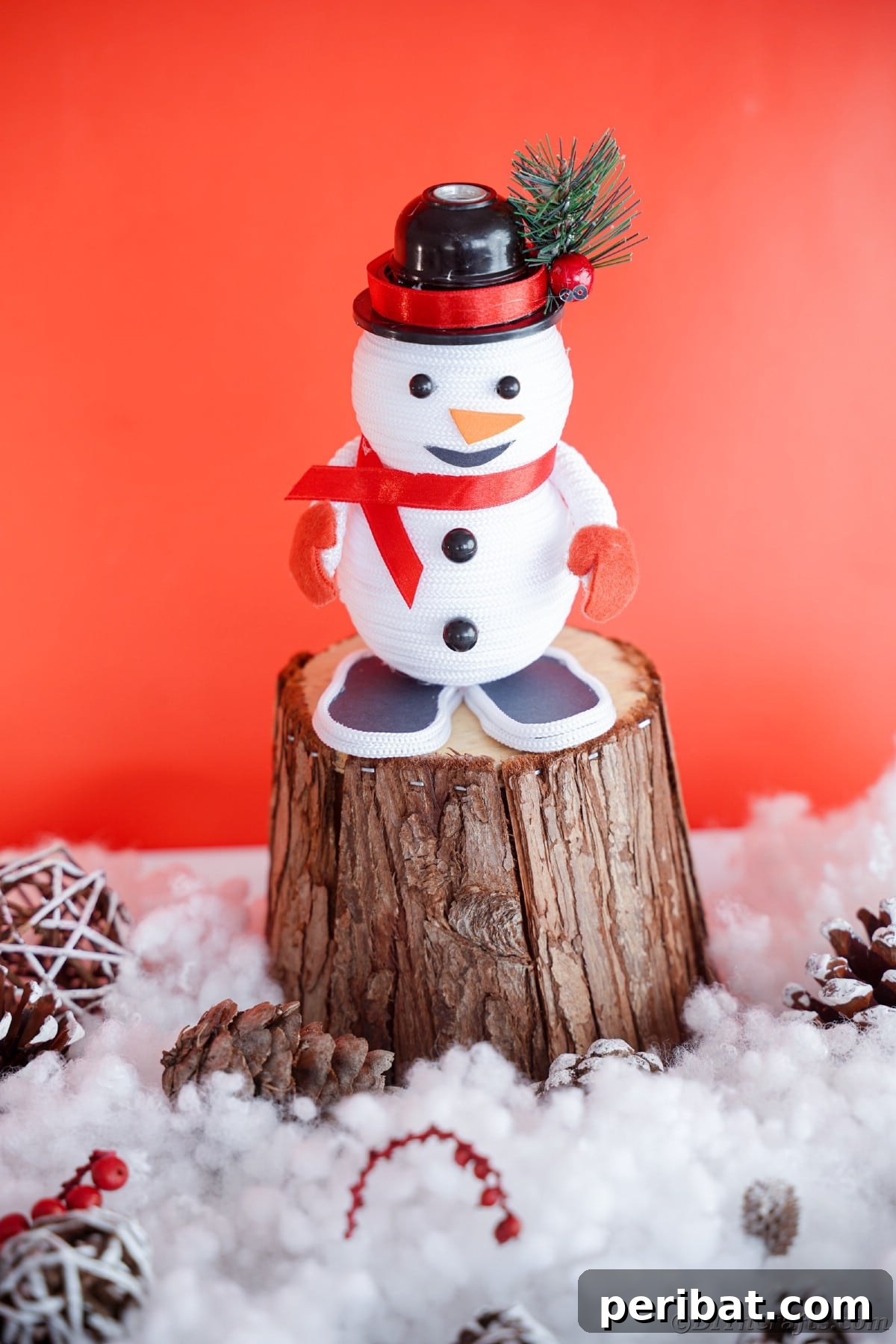 Cozy Twine Snowman Christmas Charm 4 stump on fake snow with red background holding mini snowman