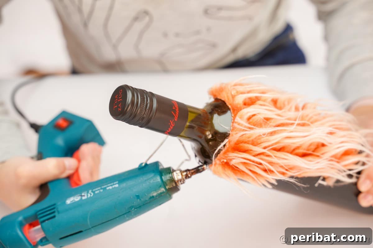 Applying hot glue to the orange fake fur and attaching it to the wine bottle to create the gnome's beard.