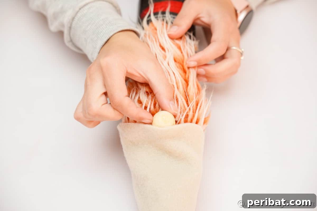Gently gluing a wooden bead at the base of the hat, resting on the orange gnome beard, to form the gnome's nose.