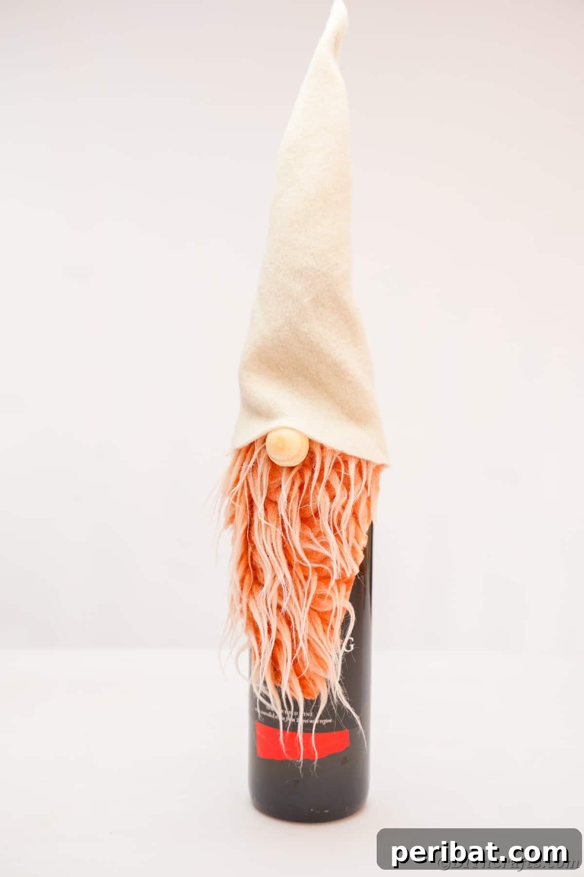 A charming gnome wine bottle cover standing on a white table, ready to be presented as a thoughtful hostess gift.