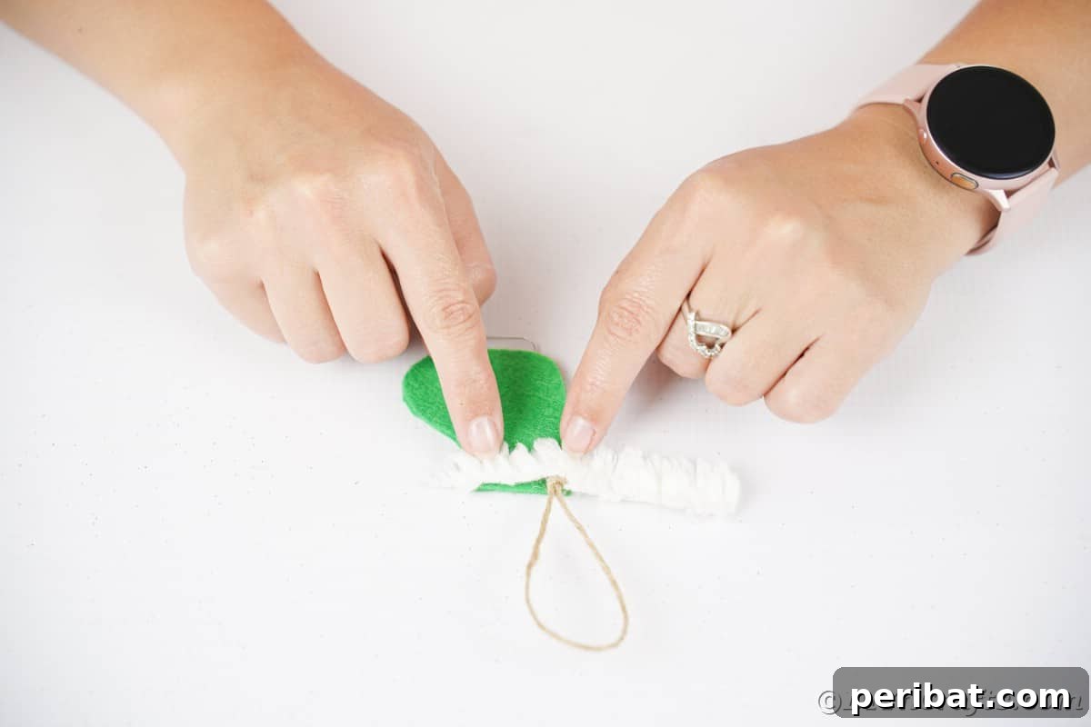 hand gluing white ribbon on top of green felt boot