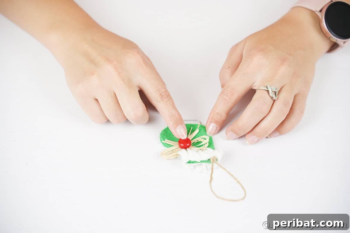 hand gluing red bead on raffia bow