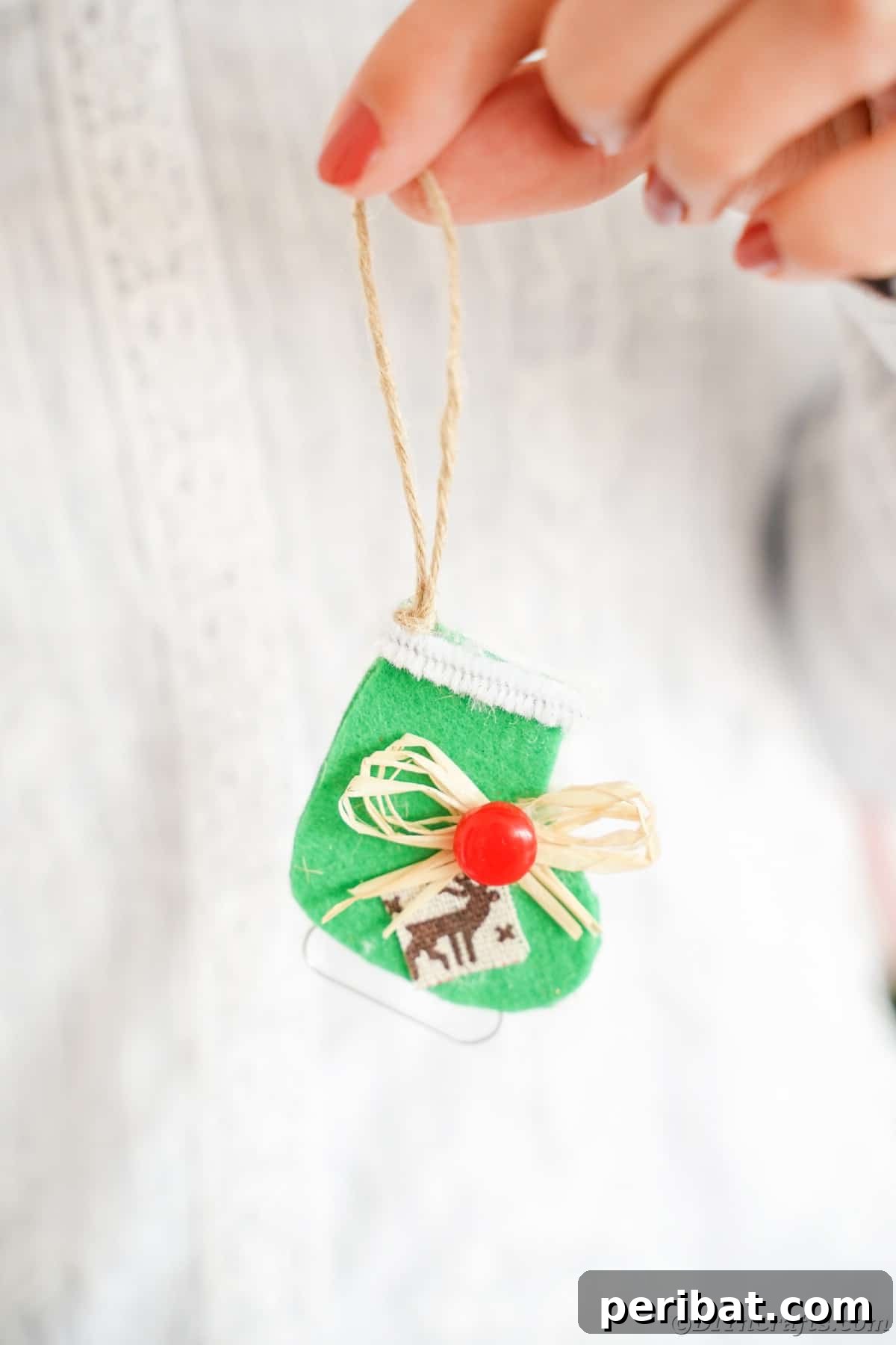 person in white sweater holding green ice skate ornament