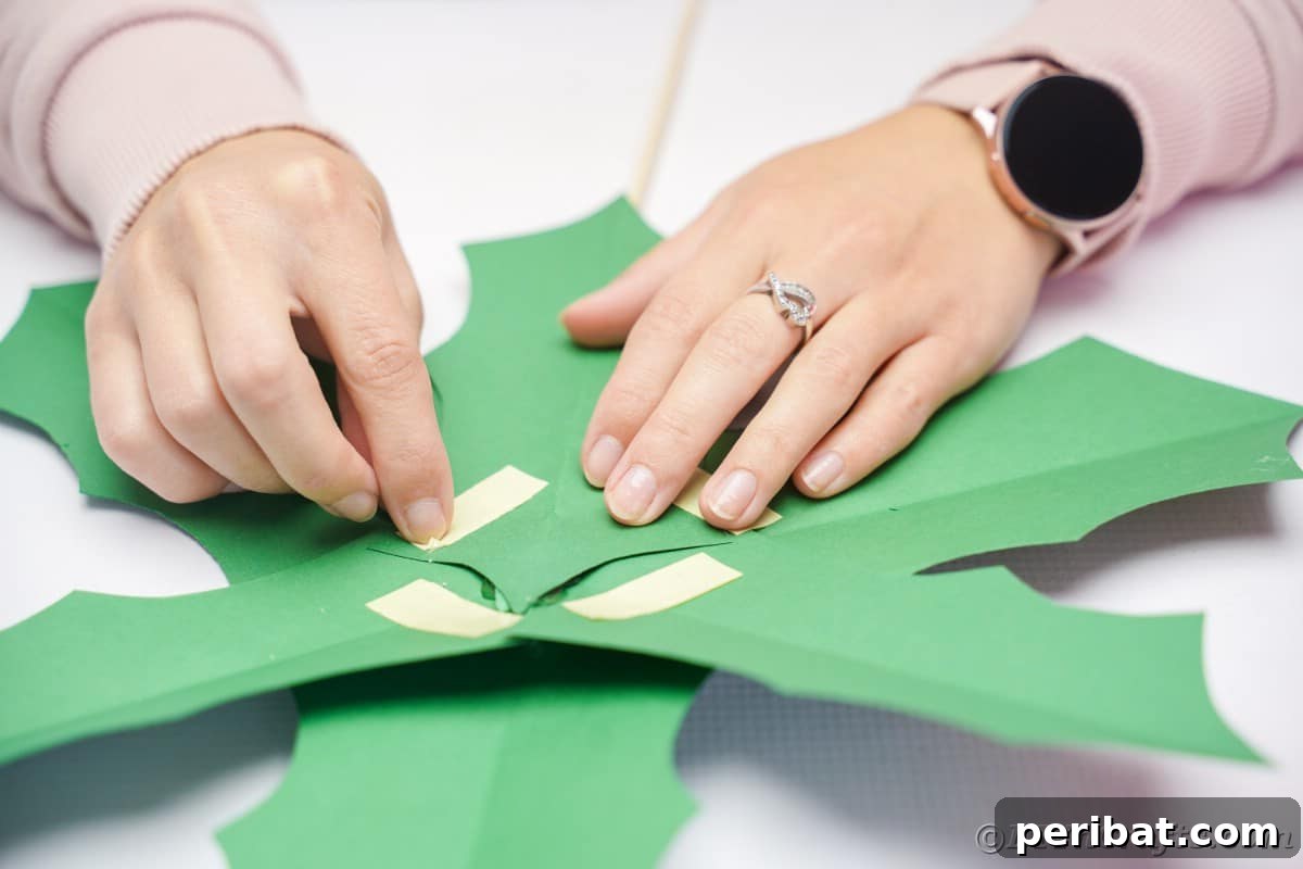 Oversized Holly Berry and Leaf Festive Decor 15 hands putting tape on back of green paper