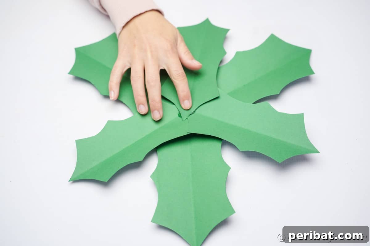 Oversized Holly Berry and Leaf Festive Decor 20 hand holding paper leaves on top of each other