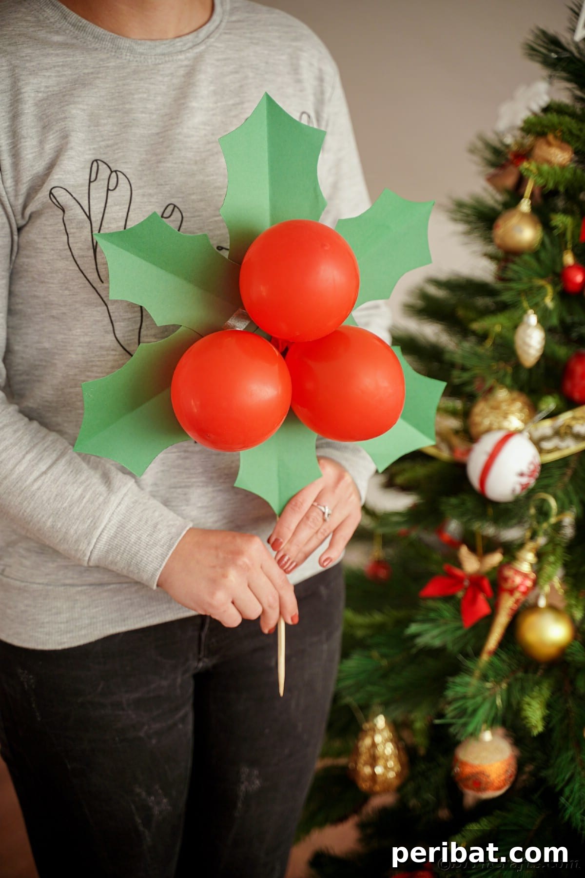 Oversized Holly Berry and Leaf Festive Decor 4 woman holding giant Christmas decoration by tree