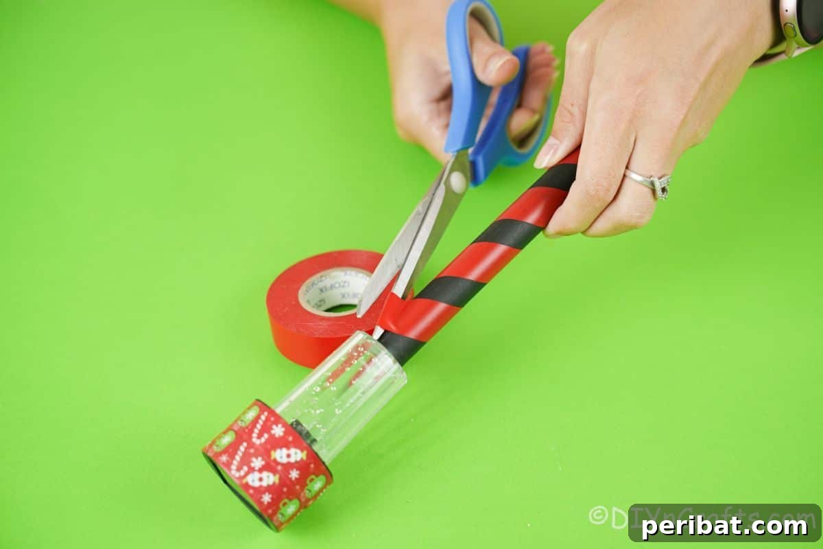 Whimsical Arctic Lamppost Craft 11 hand cutting the end of red tape on solar light