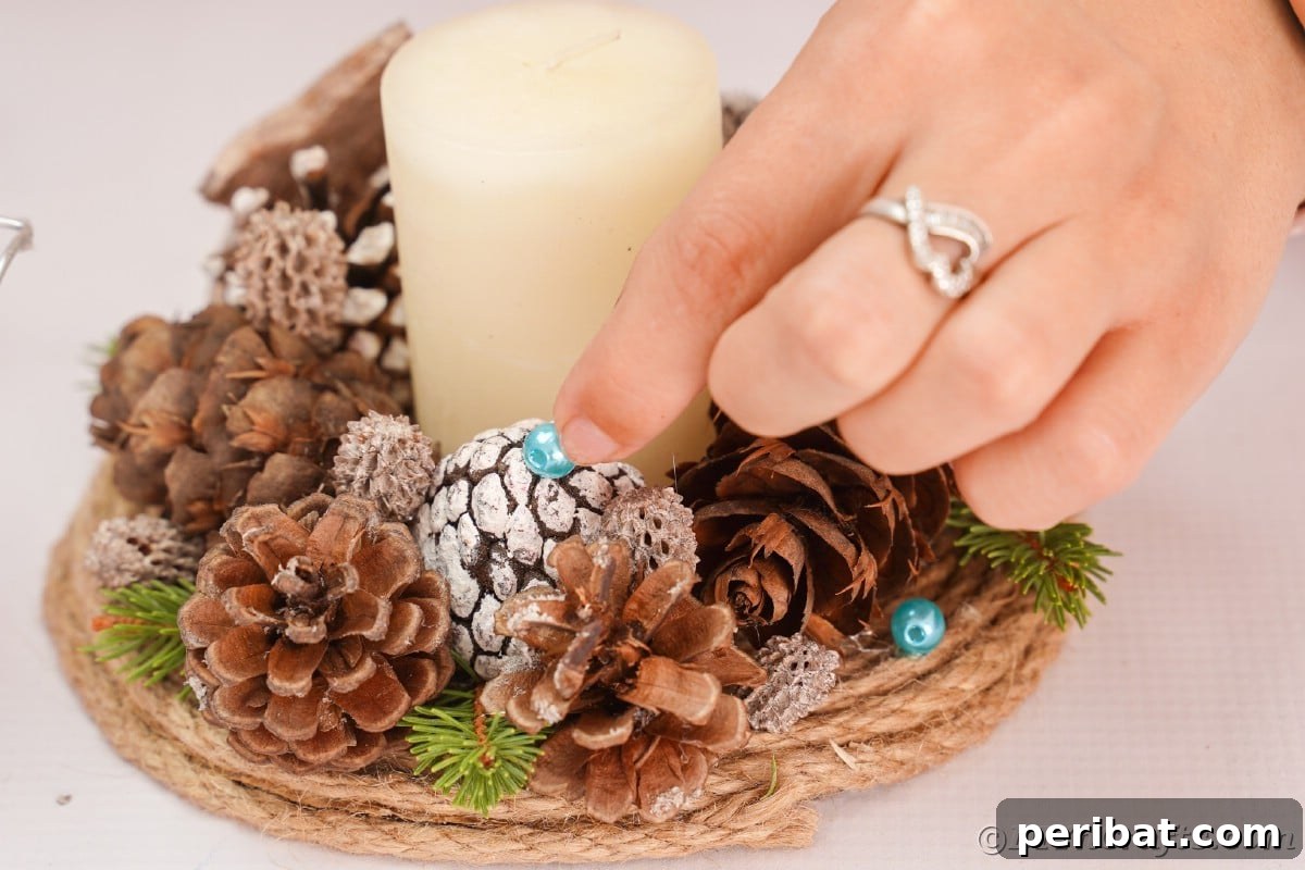 Cozy Farmhouse Christmas Candle Centerpiece 13 hand holding bead on top of pinecone