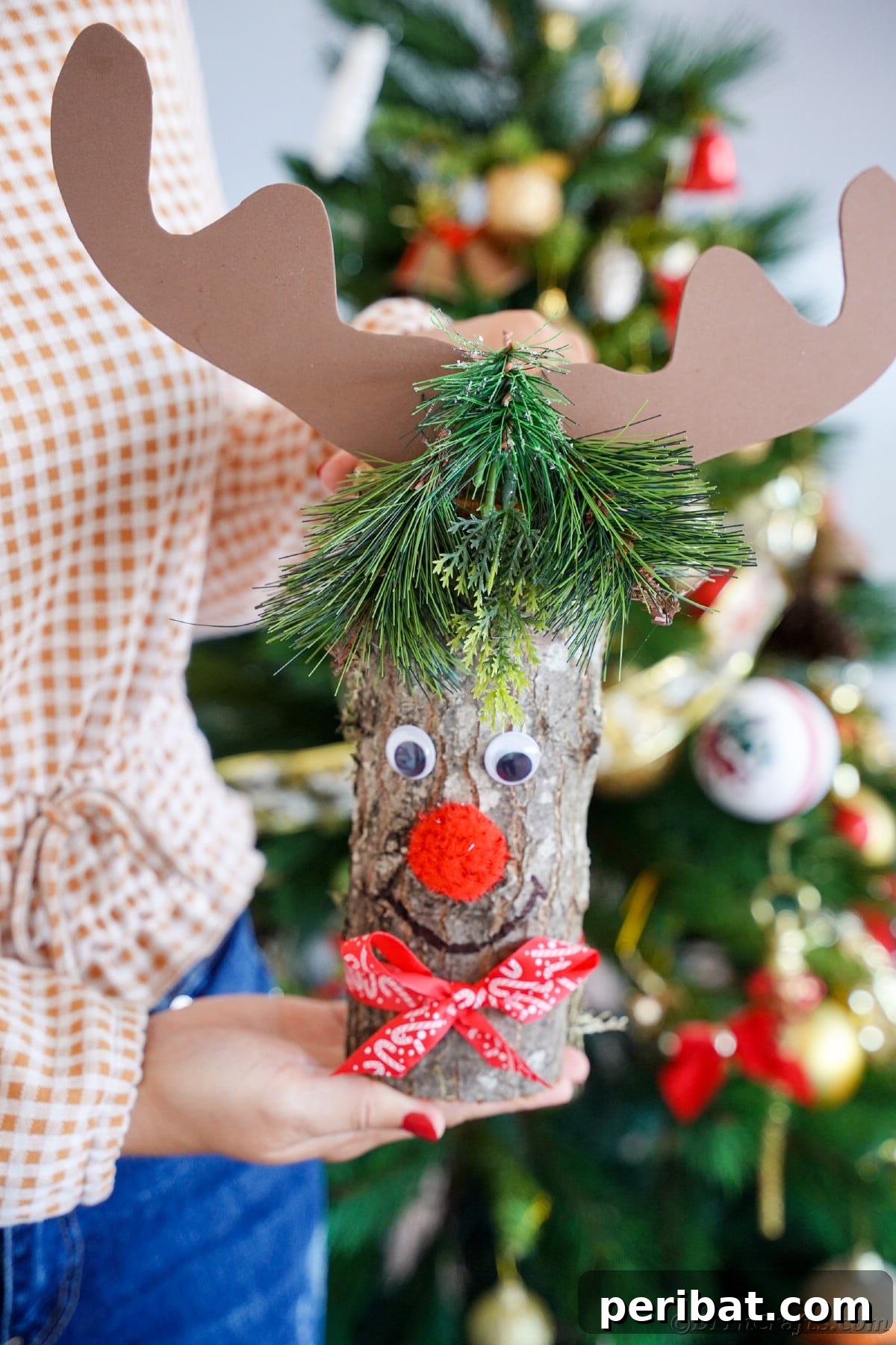 Whimsical Woodland Log Reindeer Decor 4 reindeer decoration being held in front of tree