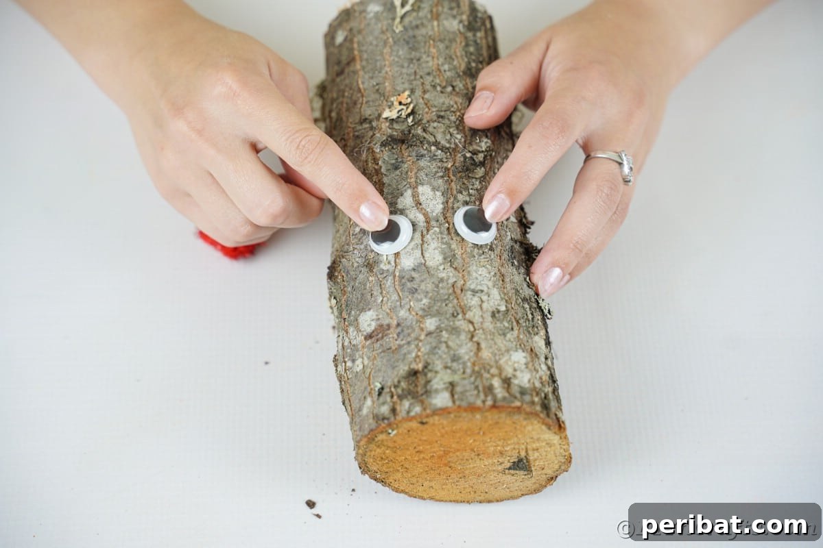 Whimsical Woodland Log Reindeer Decor 9 hand putting googly eyes on piece of wood
