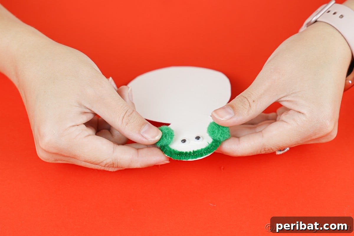 Simple Snowman Christmas Card Craft for Children 13 hand holding paper snowman adding green pom poms on head