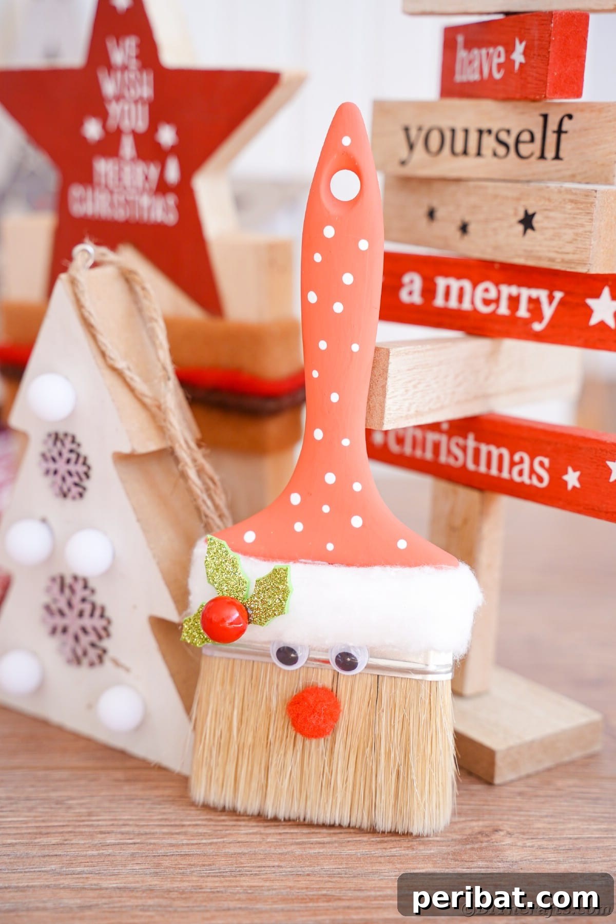A beautifully crafted paintbrush Santa Claus decoration positioned in front of a festive 'Merry Christmas' sign, showcasing its festive charm.