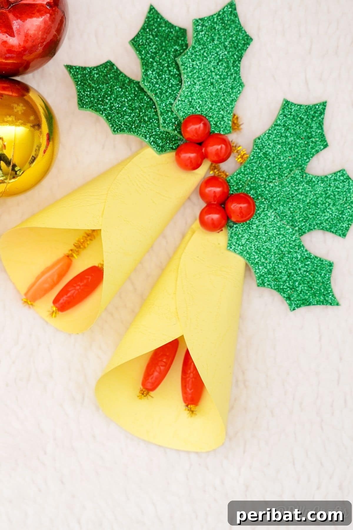 Handcrafted Paper Holly Christmas Ornament 4 paper holly leaf with bells on a table, showcasing different embellishment options