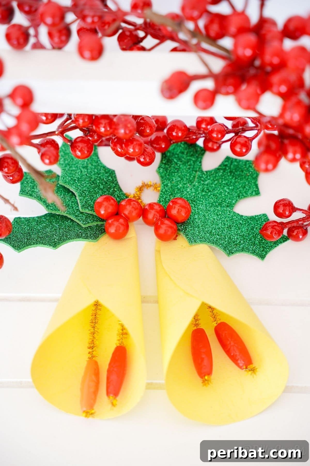 Handcrafted Paper Holly Christmas Ornament 10 yellow paper bells with holly leaves on white table, clean and bright presentation