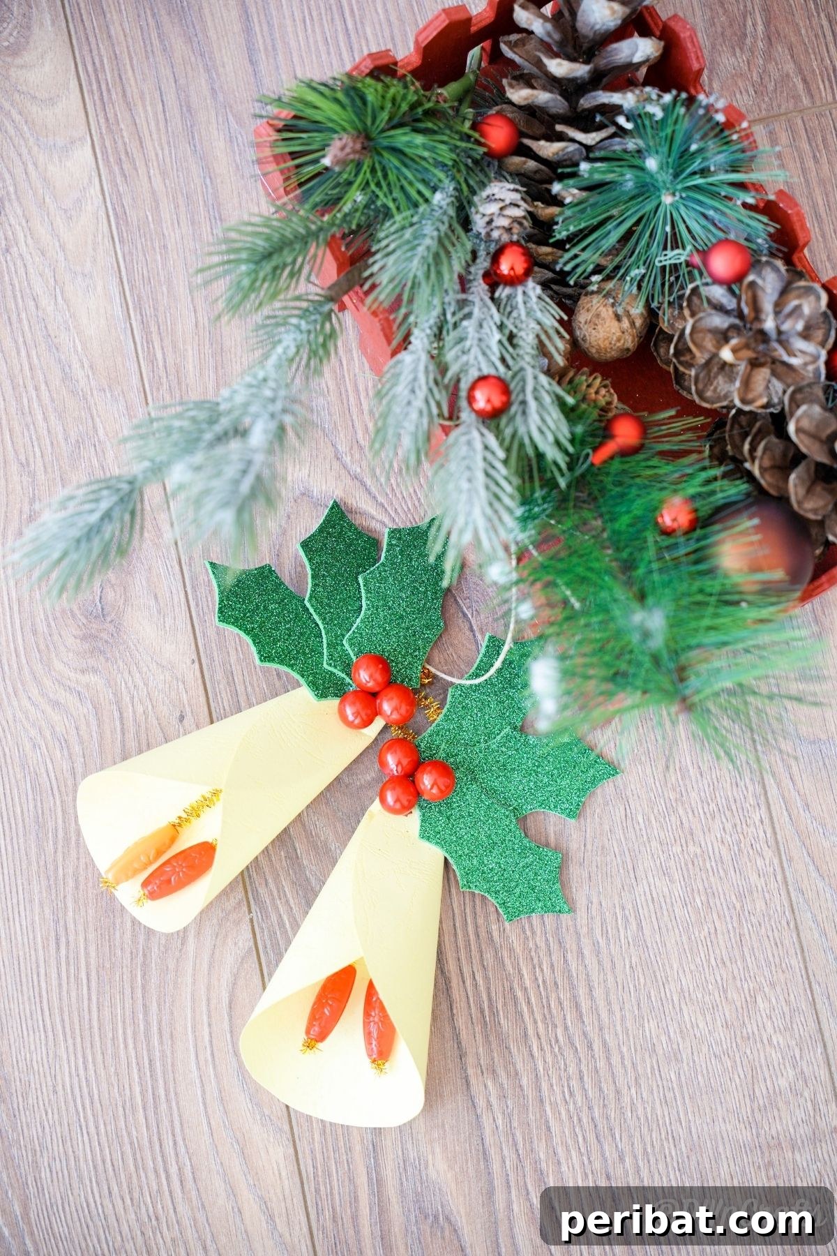 Handcrafted Paper Holly Christmas Ornament 6 yellow bell holly leaf ornament on table with pinecones, showcasing a complete crafted item