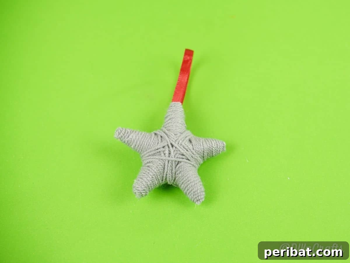 Charming Rustic Yarn Star Tree Ornament 12 gray star with red ribbon laying on green paper