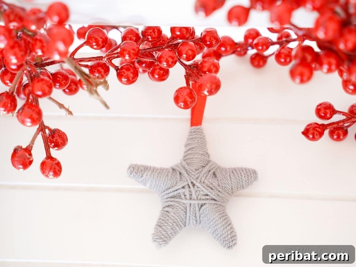 Charming Rustic Yarn Star Tree Ornament 3 gray star on white table below red berries