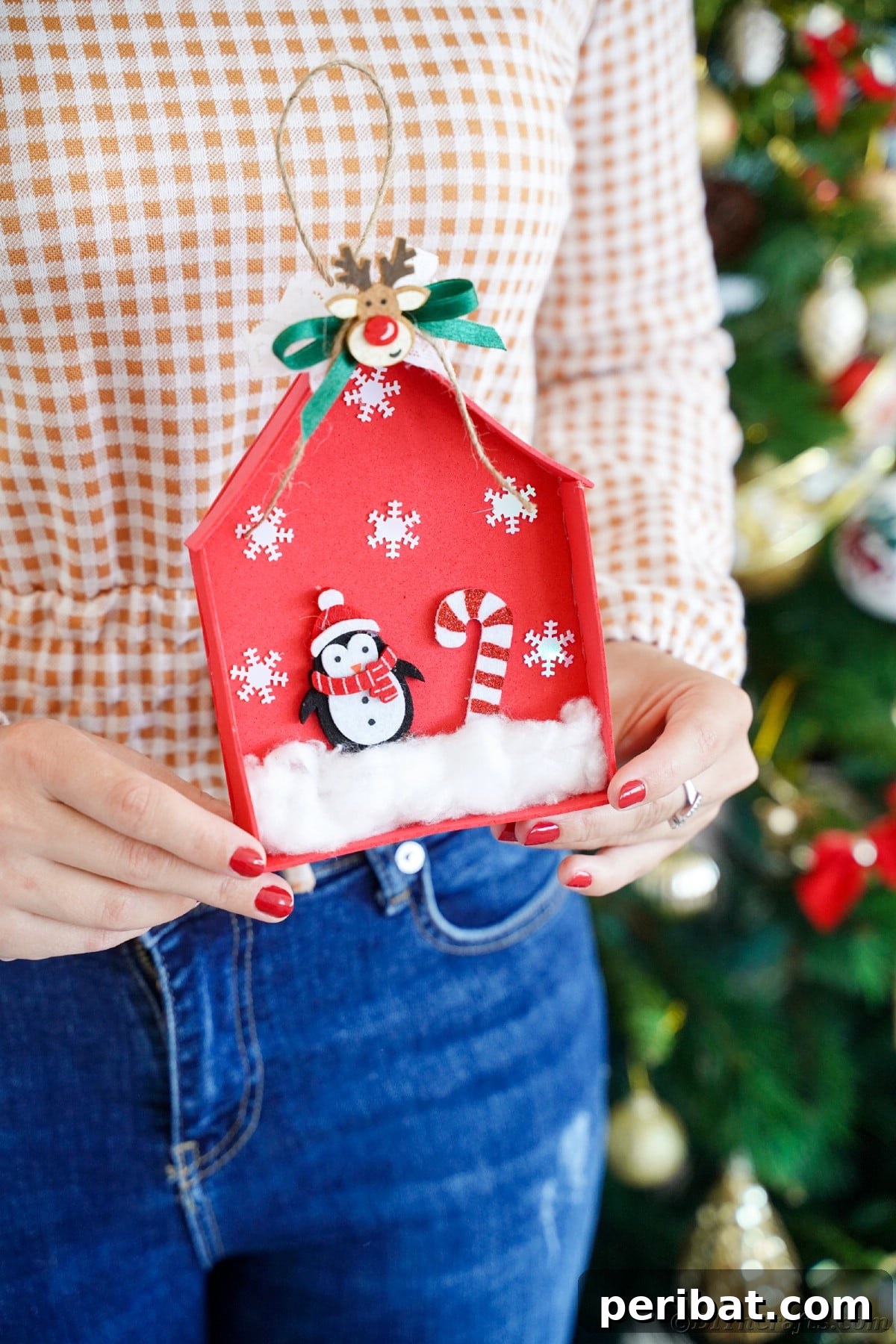 Whimsical Foam Penguin House Tree Ornament 18 A woman in jeans holding up the red penguin house ornament, highlighting its size and detail