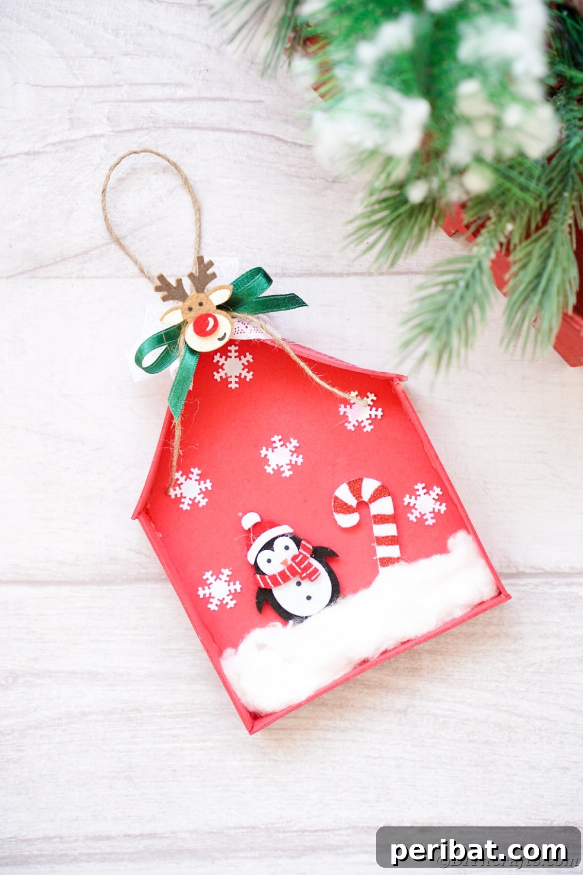 Whimsical Foam Penguin House Tree Ornament 20 A mini red house ornament resting on a white board, showcasing its intricate details and festive design