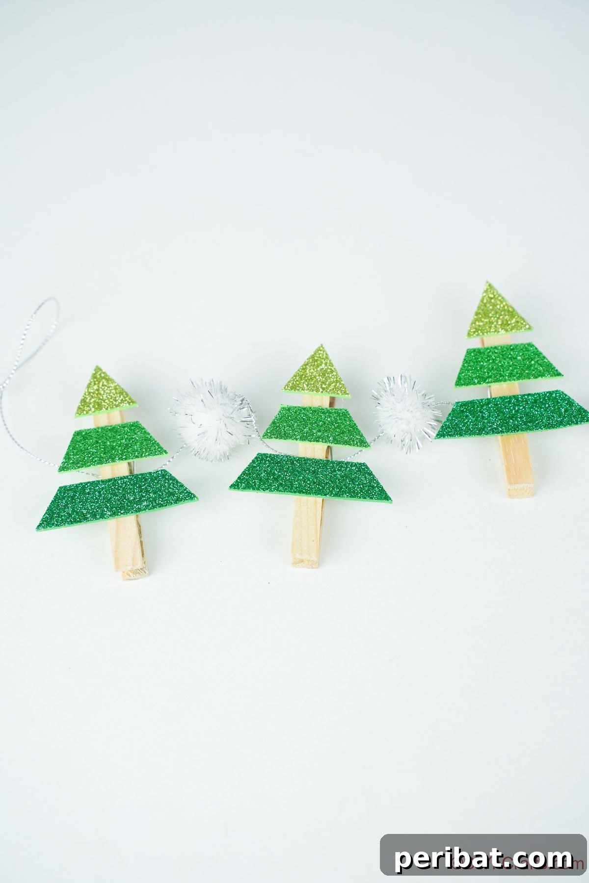 three green mini trees on clothespins on white table