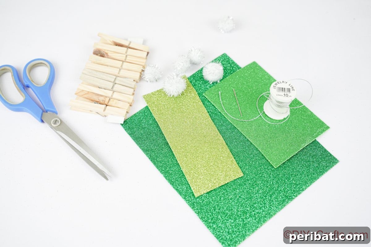 white table holding green paper clothespins and pom poms