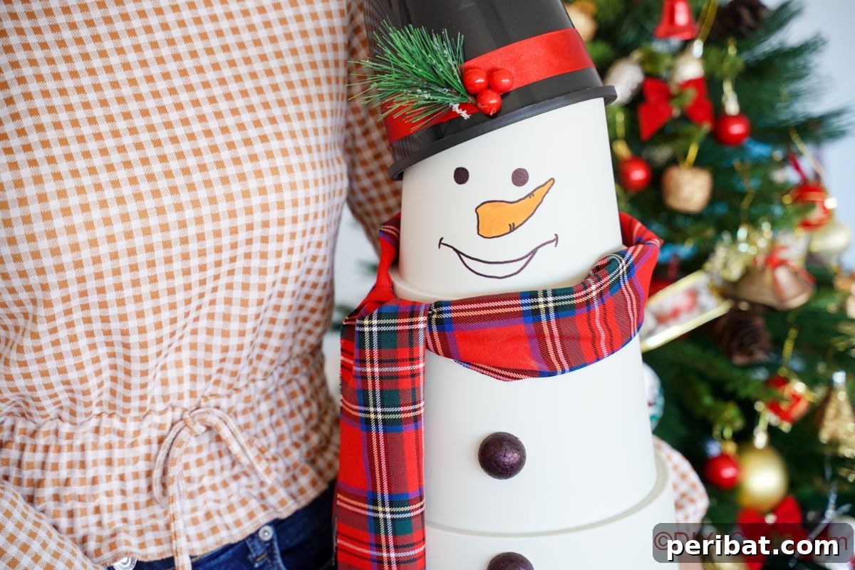 Close-up of a person holding a handcrafted flower pot snowman, showcasing its tiered design